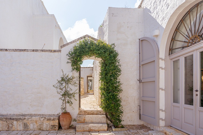 Masseria Petrarolo courtyard entrance with stone arch and climbing greenery