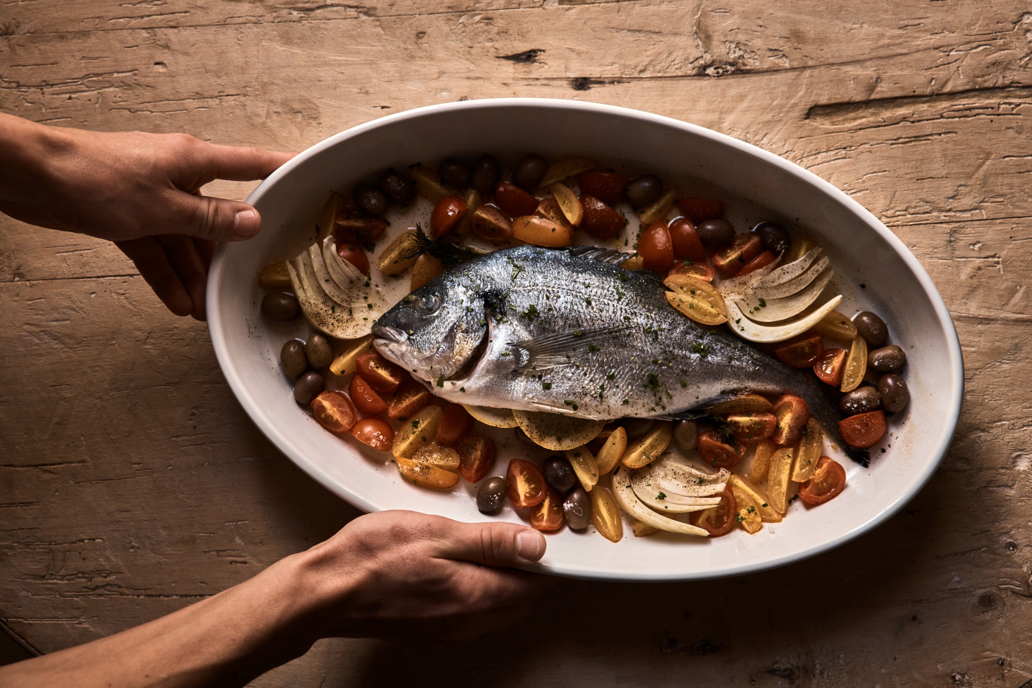 Whole baked fish with tomatoes, olives and lemon