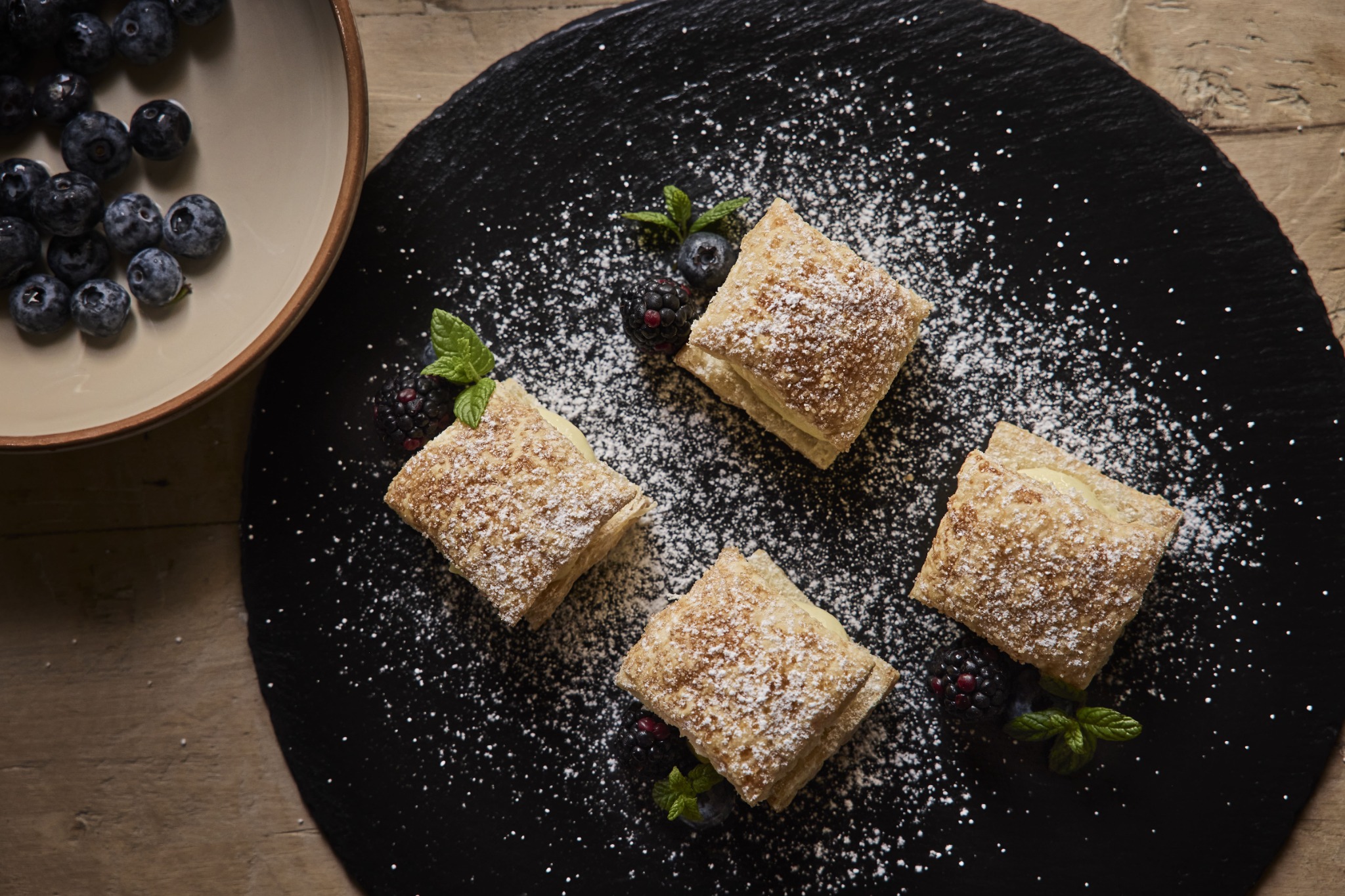 Cream-filled pastries with berries and a dusting of icing sugar