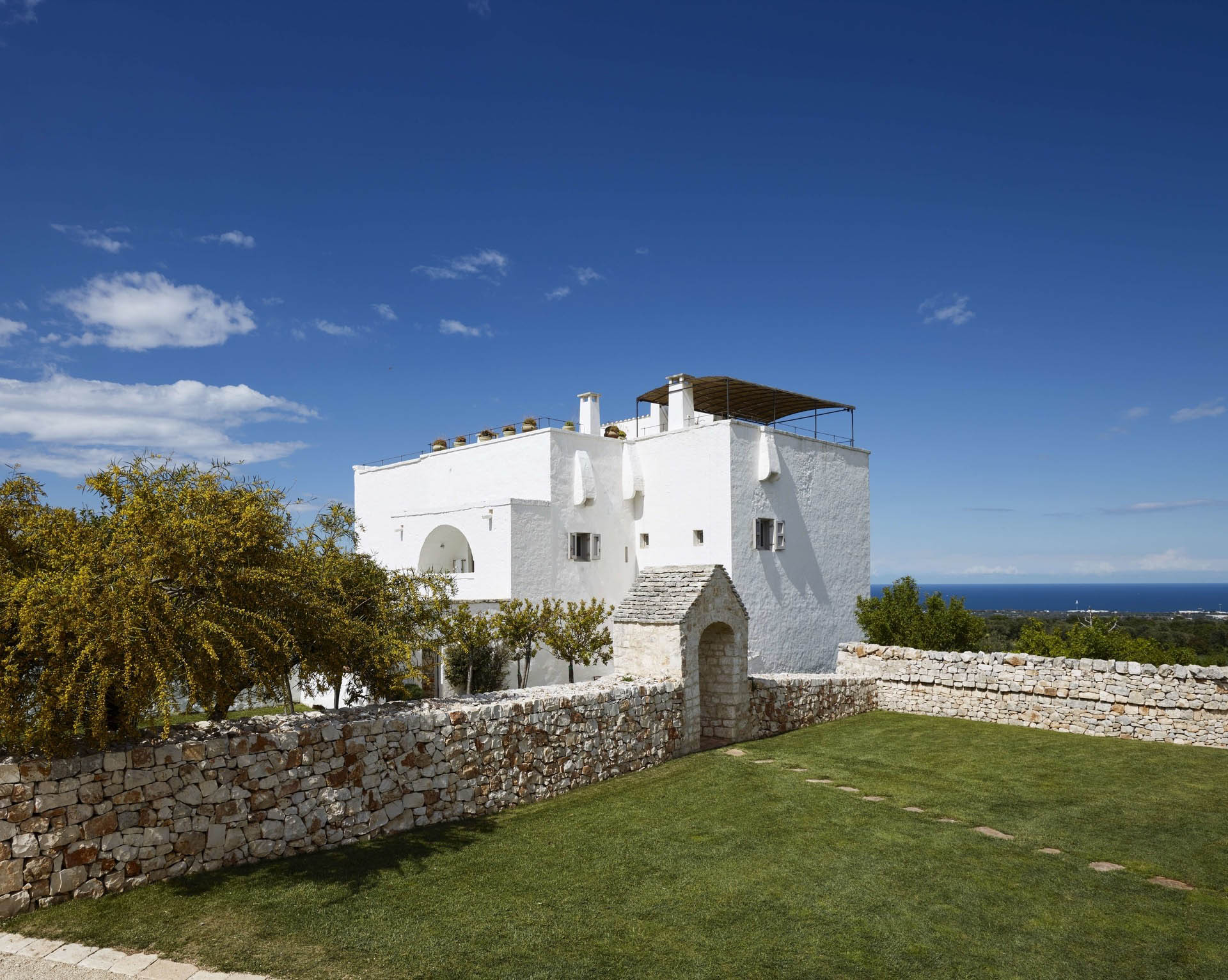 The historic white Masseria above its walled gardens, with the Adriatic beyond